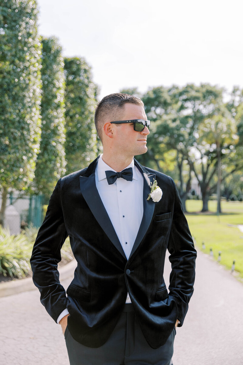 Groom standing outside in the sun wearing sunglassses