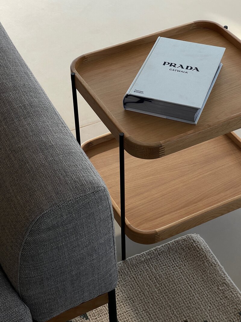 On Top a wooden table, sets a white Prada book