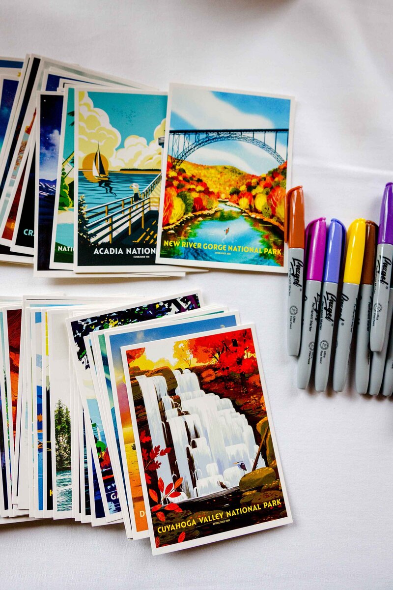 Sharpies on a table next to two stacks of National Park postcards.