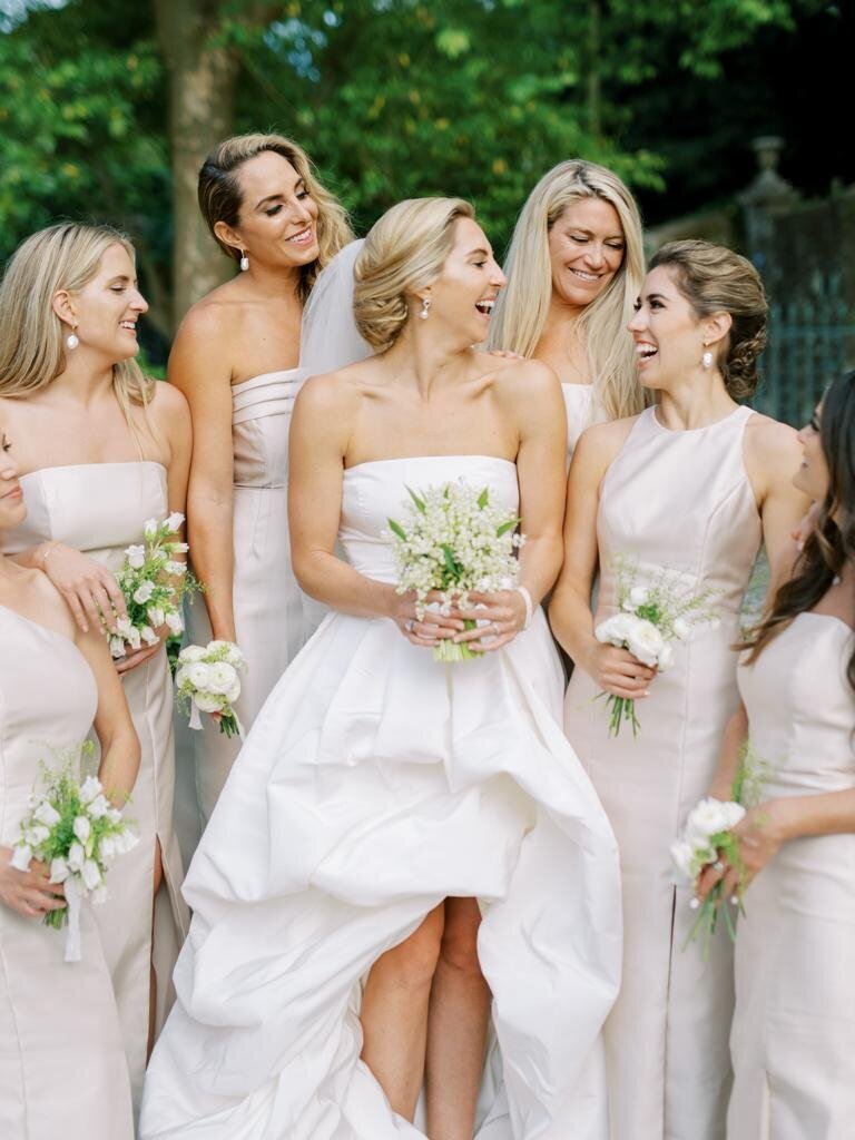 Bride and her bridesmaids with their floral lily of the valley bouquets and Oscar de la Renta gown