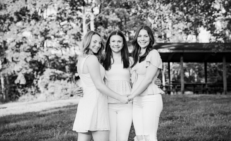 three sisters smiling and hugging during family photography session in north carolina