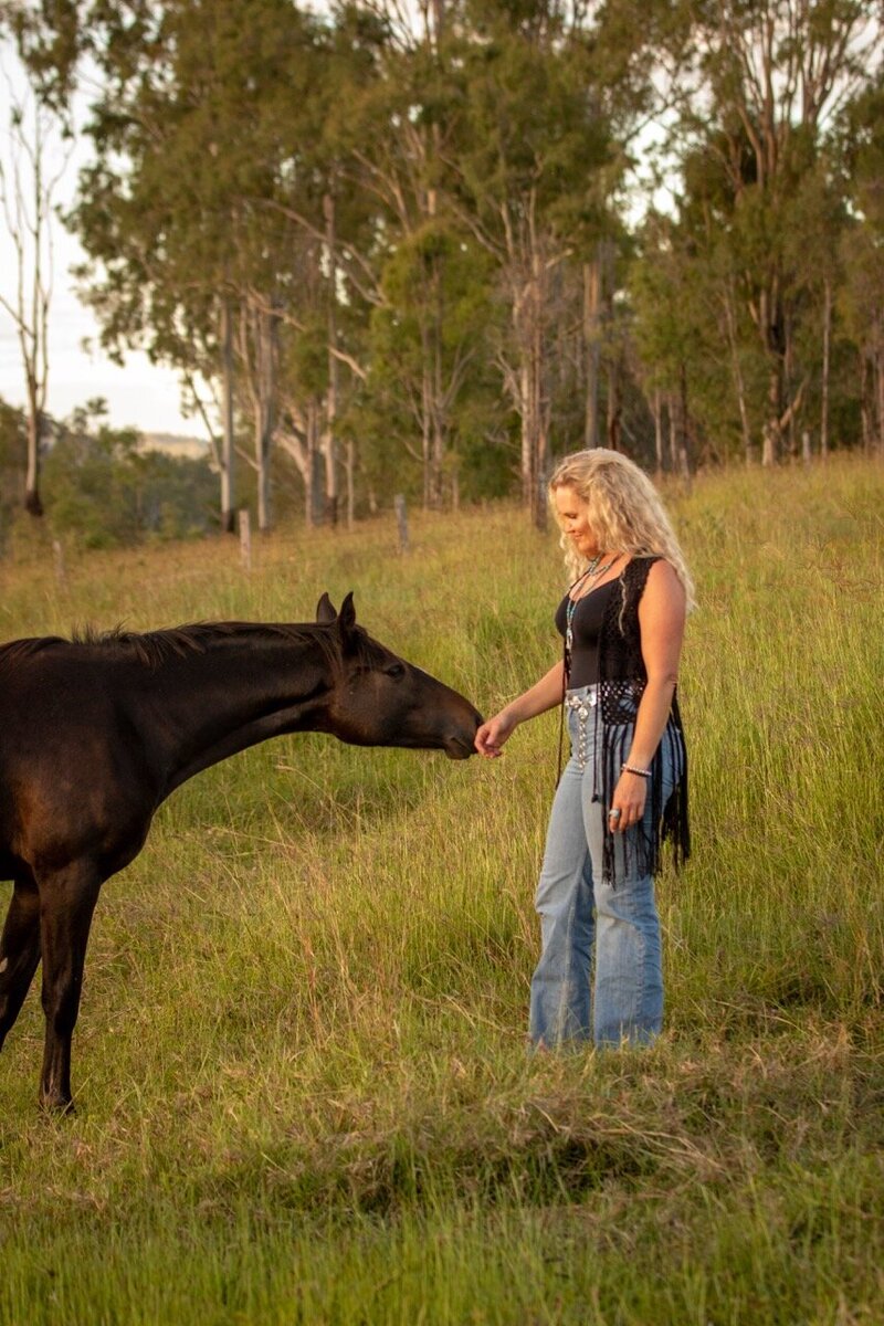 Woman with hands connecting with horse during a horse retreat in Queensland, Australia. 
