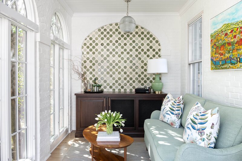 Living room with a light green couch, patterned pillows, a wooden coffee table, and unique circular wall art, creating a stylish and comfortable space