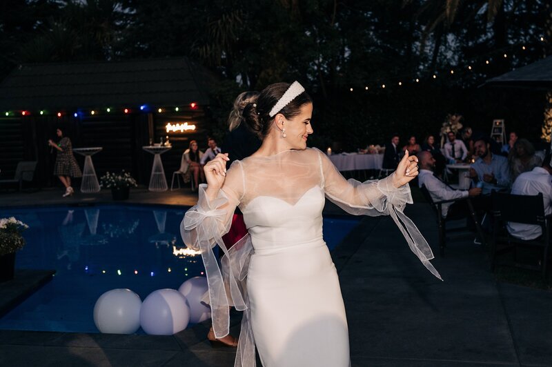 bride in trish peng dress dances beside the pool at her christchurch backyard wedding