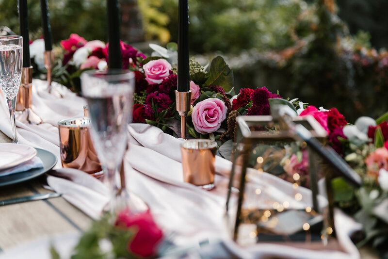 Modern romantic pink and red wedding reception table with glasses and candles