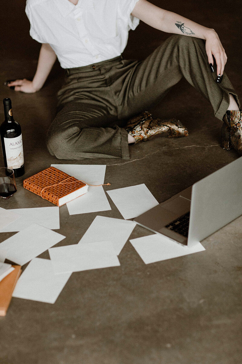 A website copywriter sitting on the floor organizing documents for a copywriting project