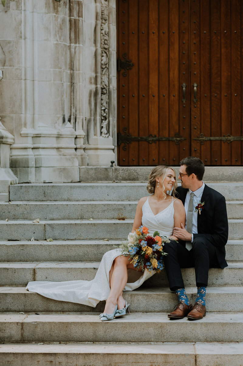 bride and groom sitting on steps of lehigh university looking lovingly at each other