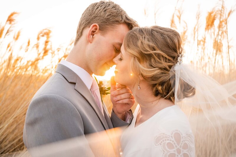 Bride and Groom sharing a kiss with golden hour light in a field in Utah for their wedding session.