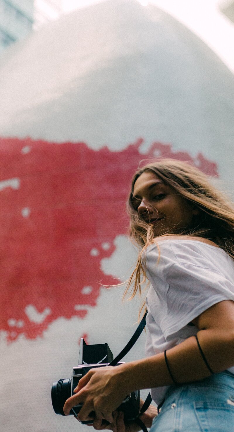 A woman with a camera in front of a mural, listing stock image sites like Pexels and Unsplash.