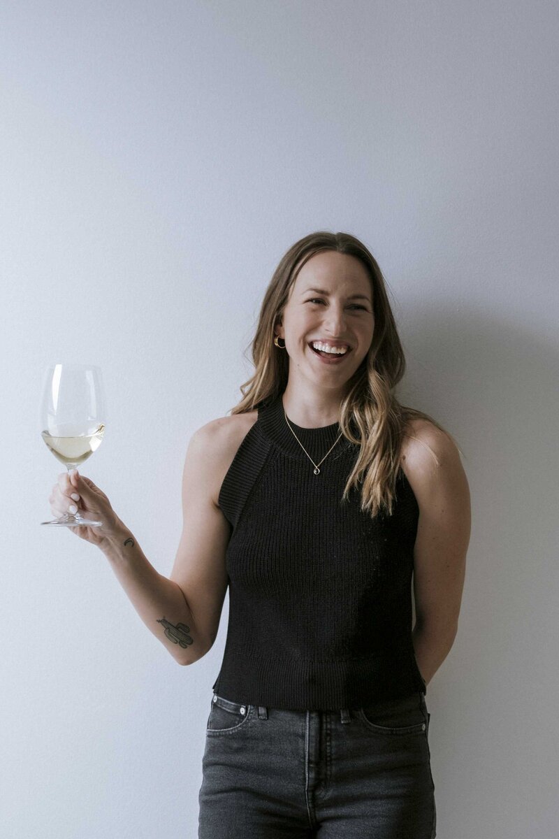 Yoga and Pilates instructor smiling and holding a glass of wine, embracing a balanced approach to wellness