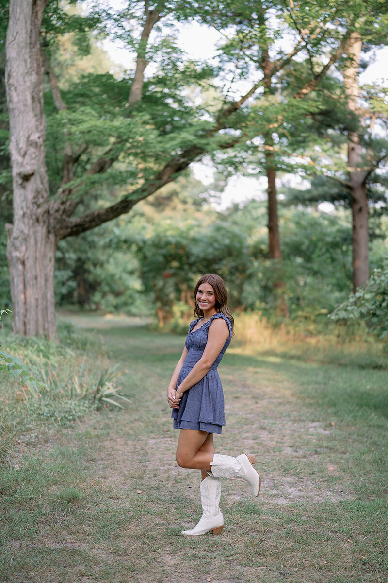 Senior posing for her photos in a denim dress and white cowgirl boots during her Michigan senior session.