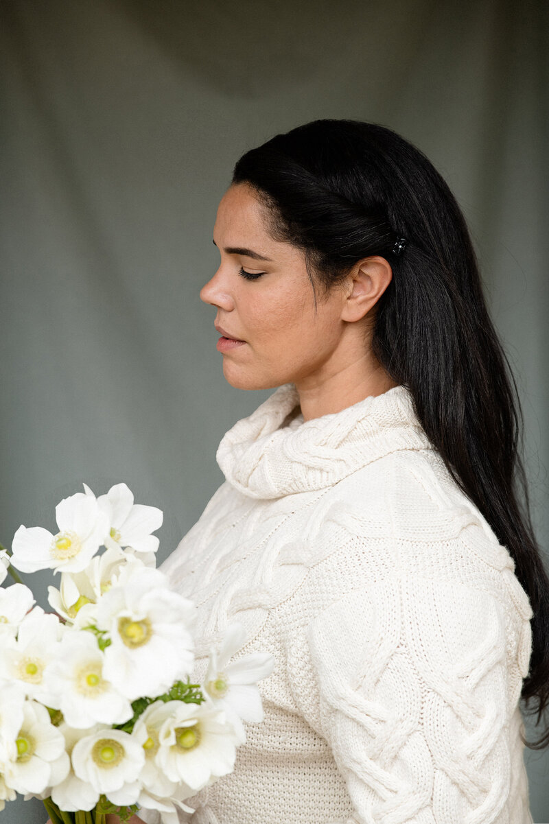 Jasmin From Idyllwild Event Design wearing a white sweater and holding a bunch of white anemones