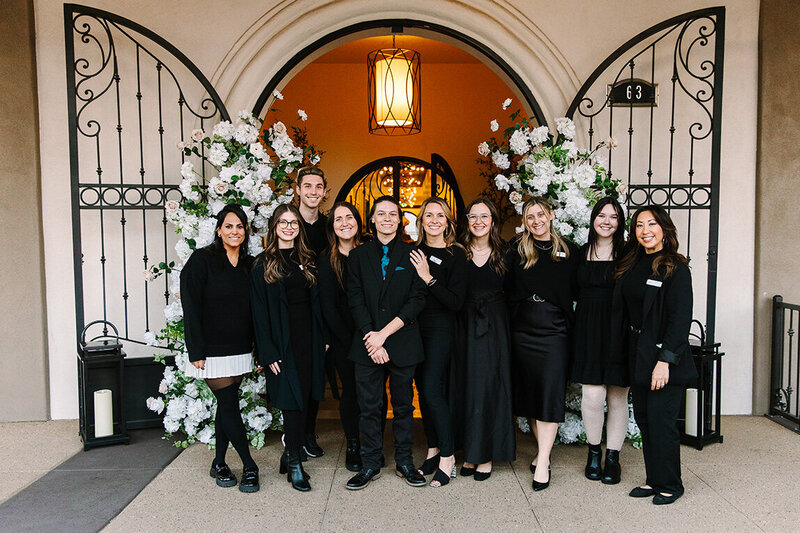 The SoHo63 team poses together in front of the venue’s signature arched entrance, framed by elegant white floral arrangements. Located in downtown Chandler, this wedding and event venue is known for its dedicated staff who help bring every celebration to life with excellence and care.
