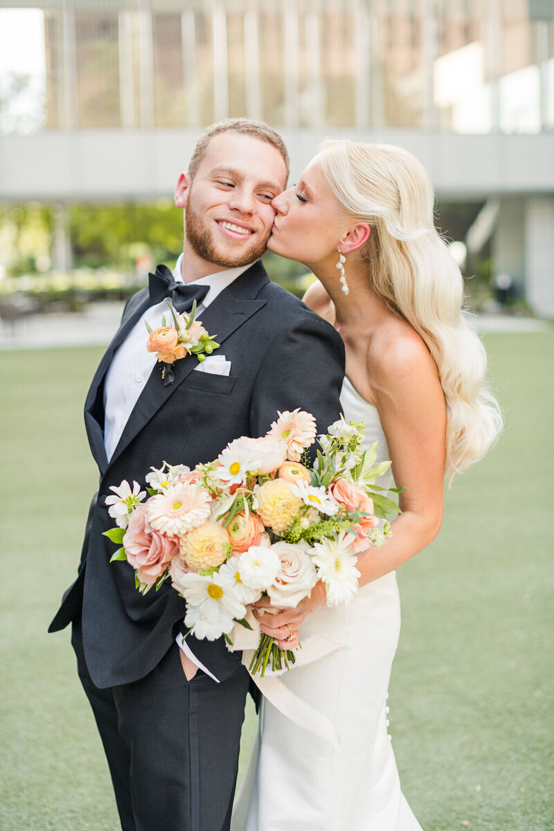 Bride kisses groom's cheek at Houston wedding.