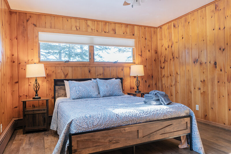 Tongue and groove bedroom with a bed and laps on each side.
