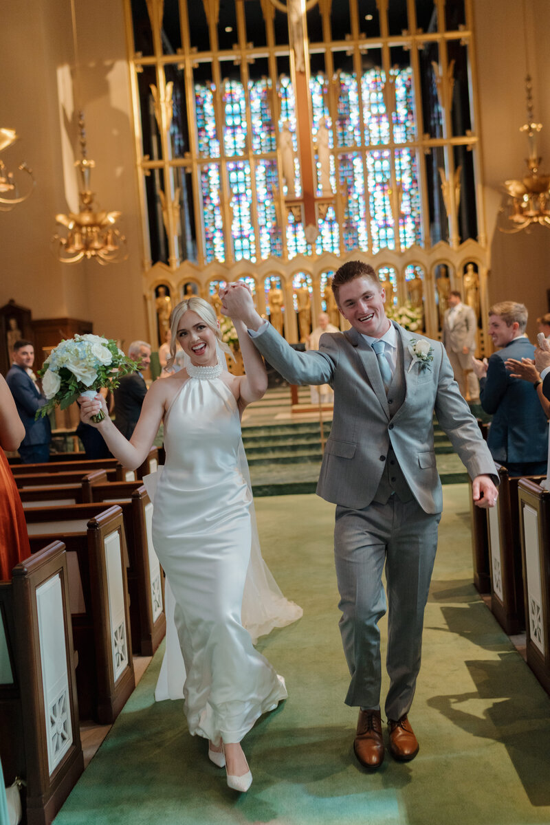 Wedding couple cheering coming down the aisle after the church ceremony in Chicago.