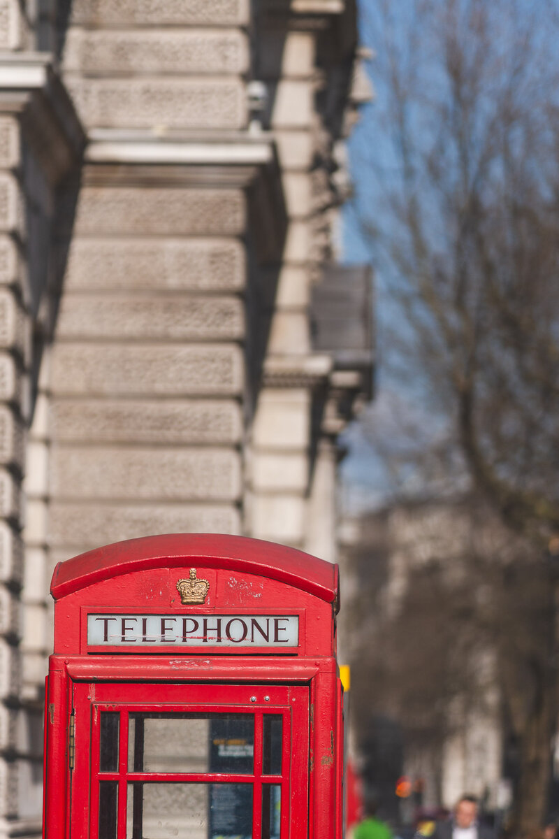 Red London phone booth next to stone building, symbolizing connection — Fort Worth photographer contact section.