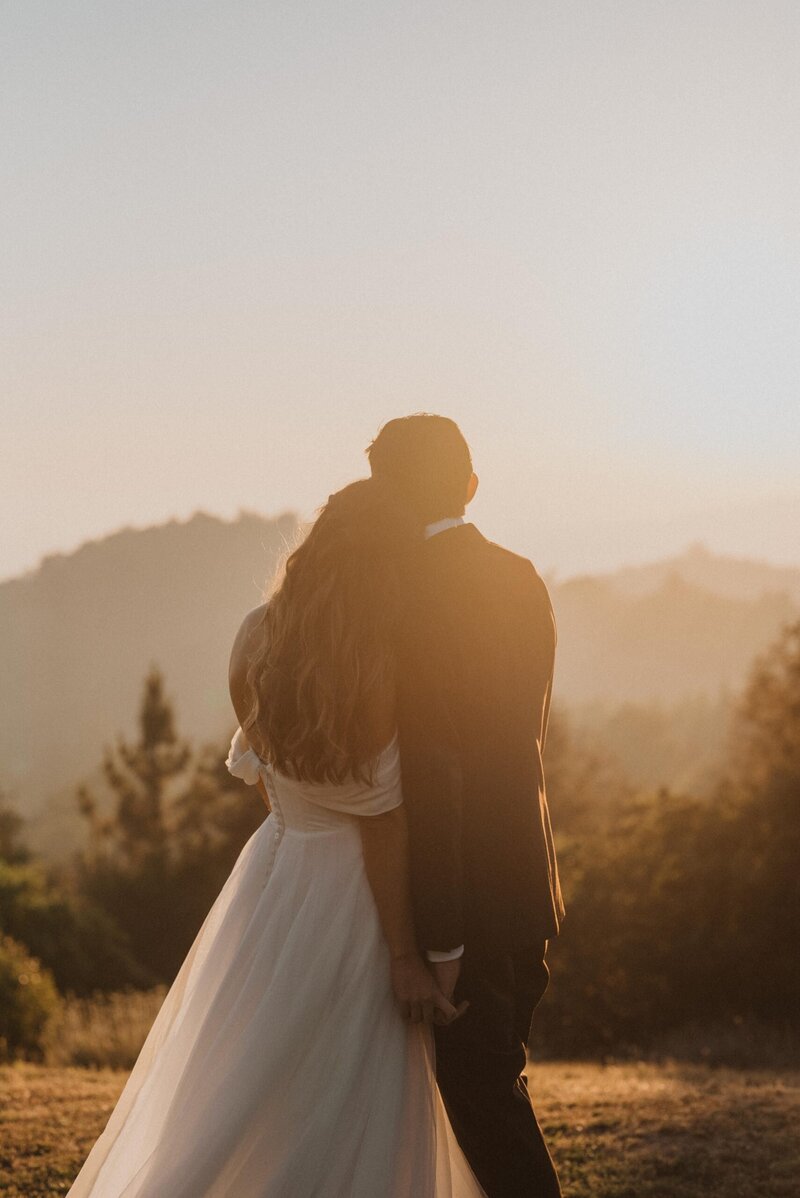 Photo of a wedding couple in wedding attire watching sunset at Sacred Mountain Ranch in Julian, California near San Diego California