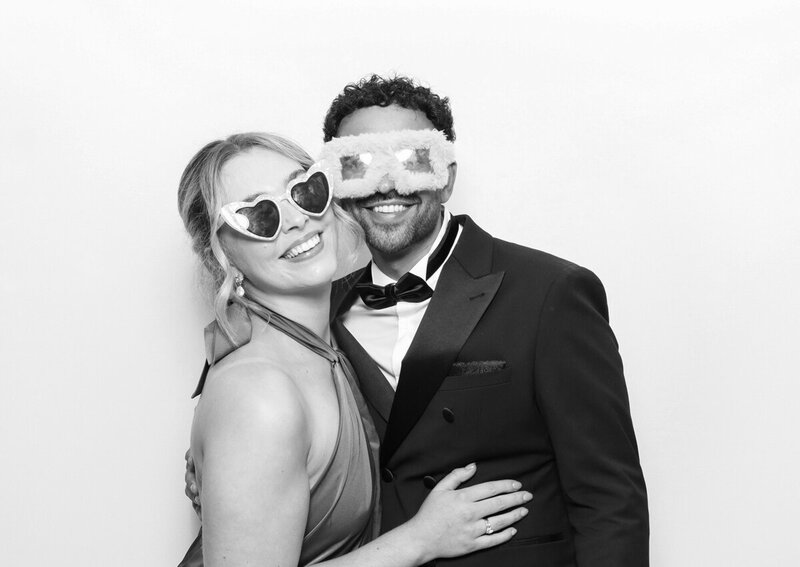Black and white filter for a print with a couple posing against a white backdrop, during a wedding party entertainment, for Mad Hat Photo Booth