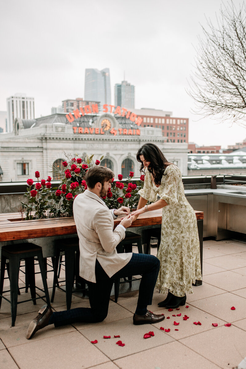 A couple gets engaged among lush red roses in front of Union Station in Minnesota, photographed by Emmie Verdell Photo.