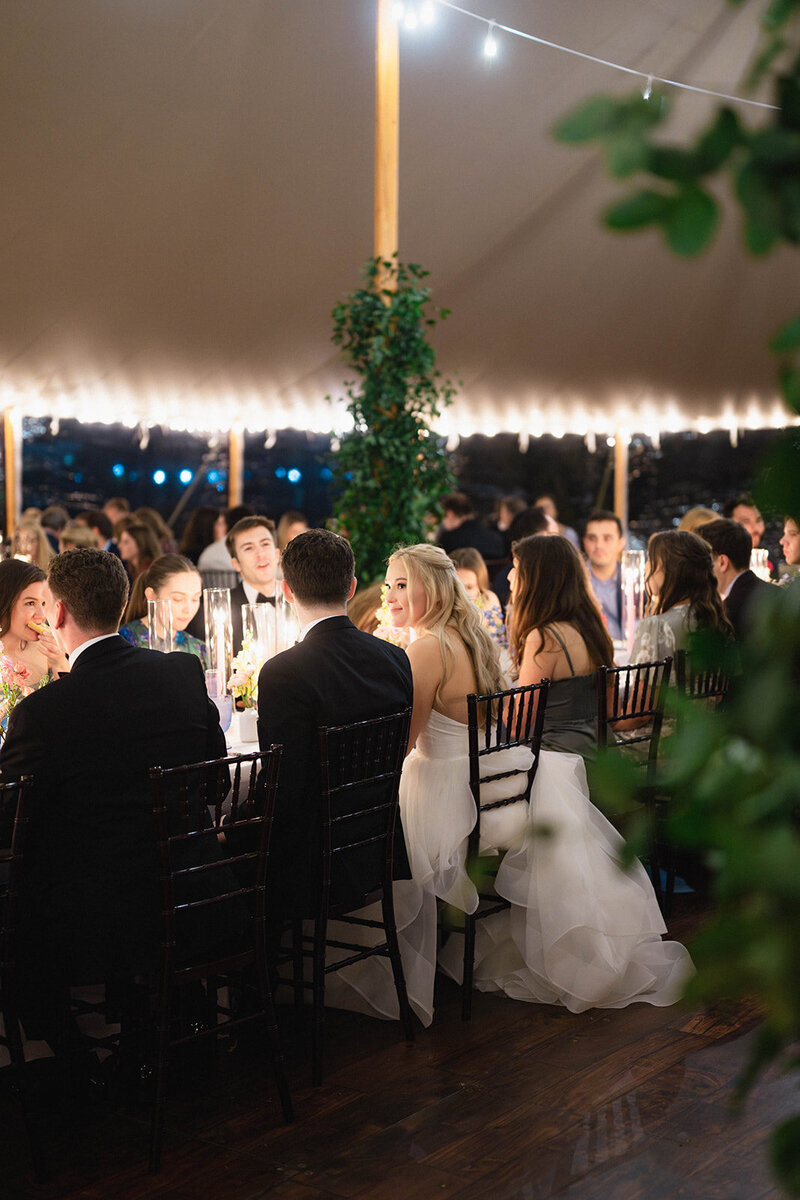 Bride and groom talk closely among guests under Sailcloth tent reception