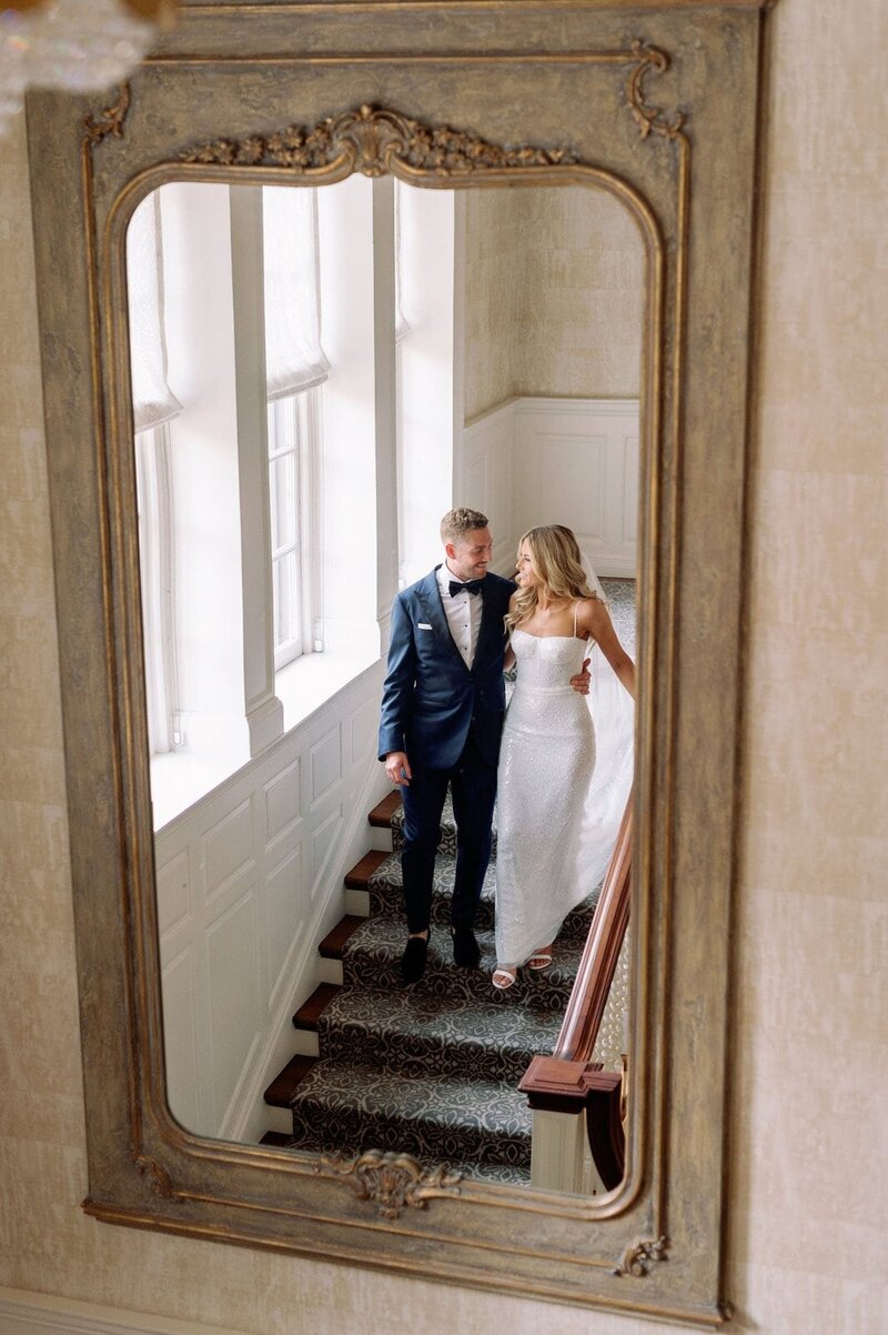 Timeless Editorial Couple walking down stairs mirror at Graydon Hall Manor Toronto Jacqueline James Photography