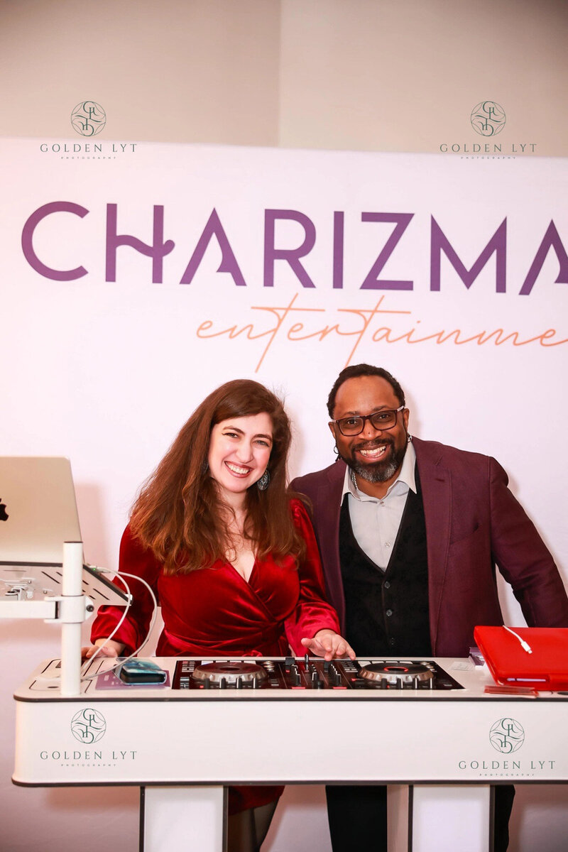 DJs smiling at booth with Charizma Entertainment sign