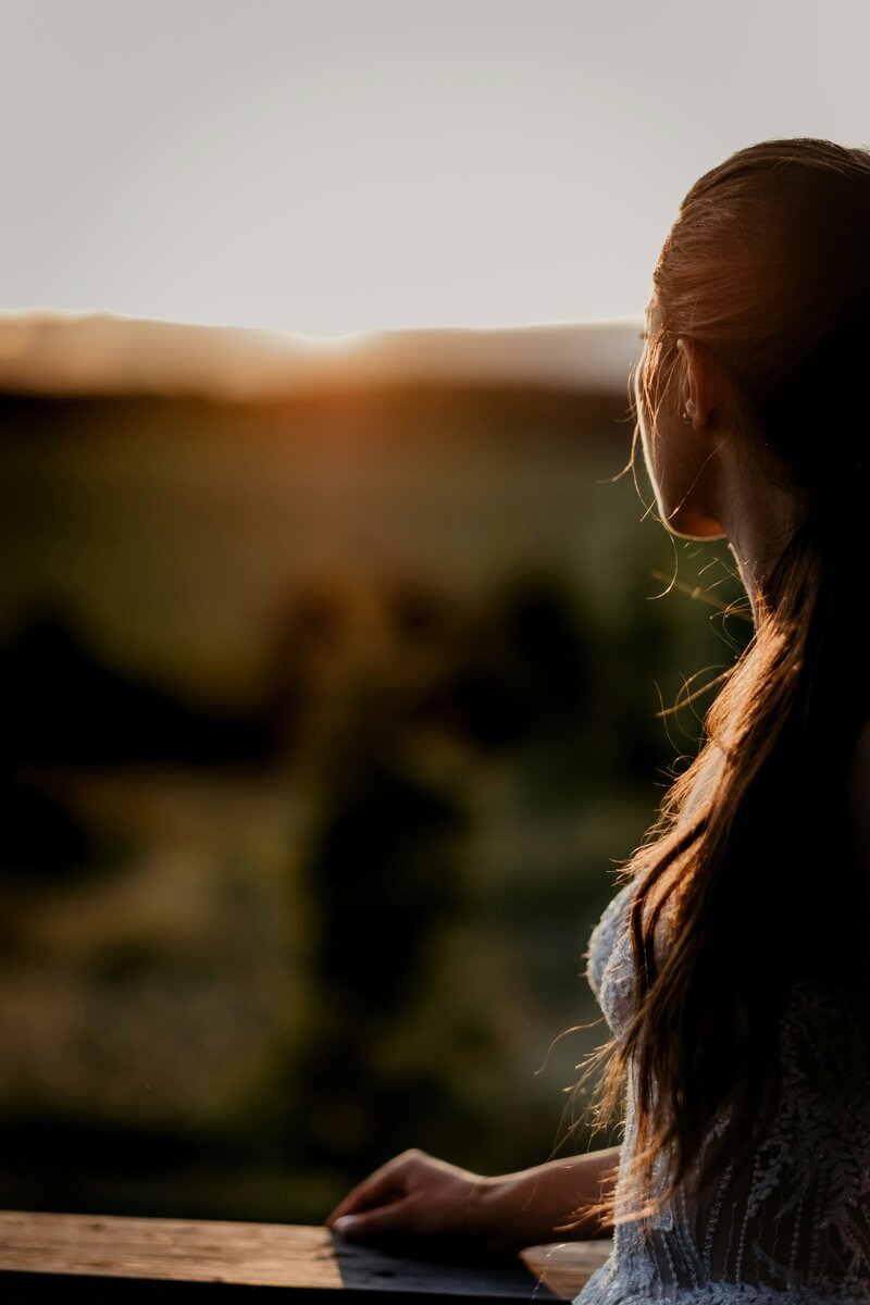 back view of sun soaked woman looking at sunset in a field