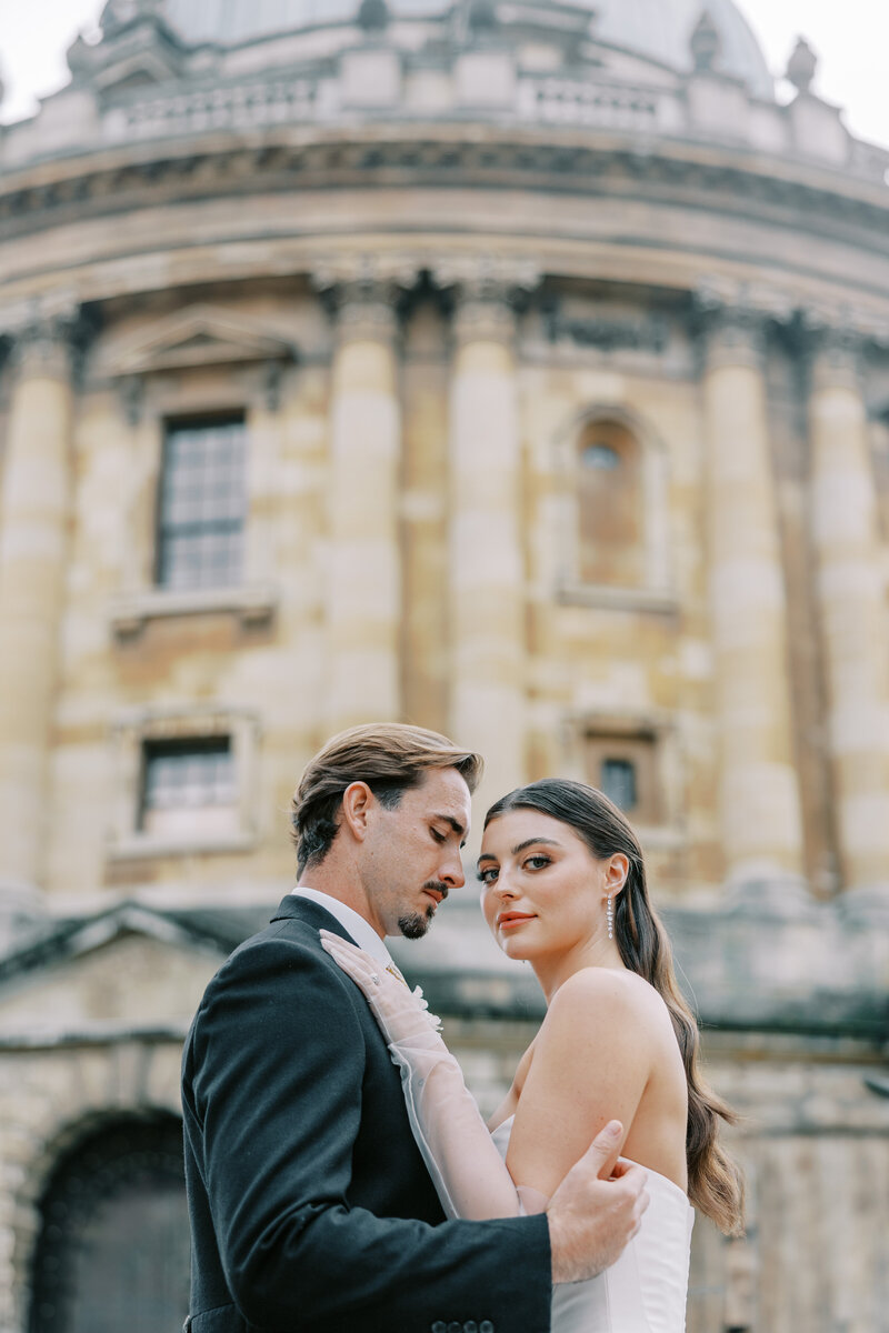 groom kissing bride on the cheek as they stand under the veil