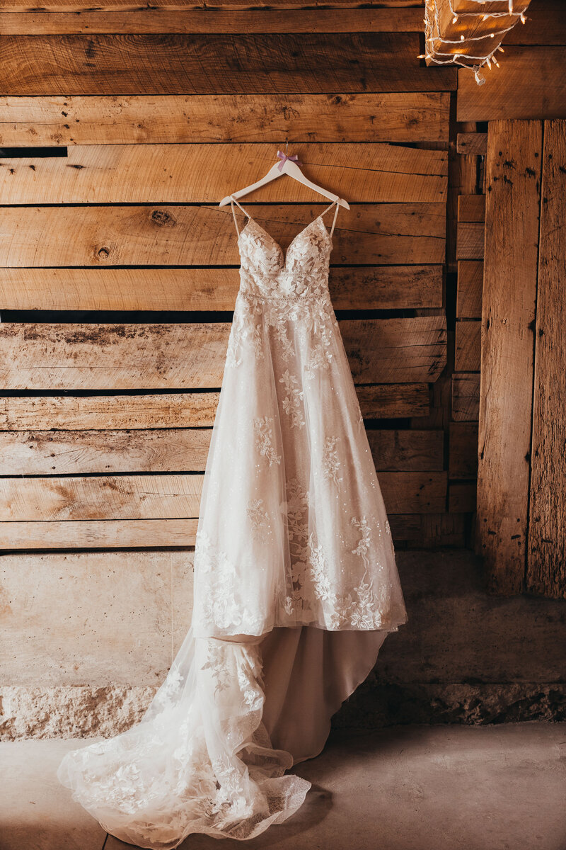 Wedding photo session of dress hanging against wall