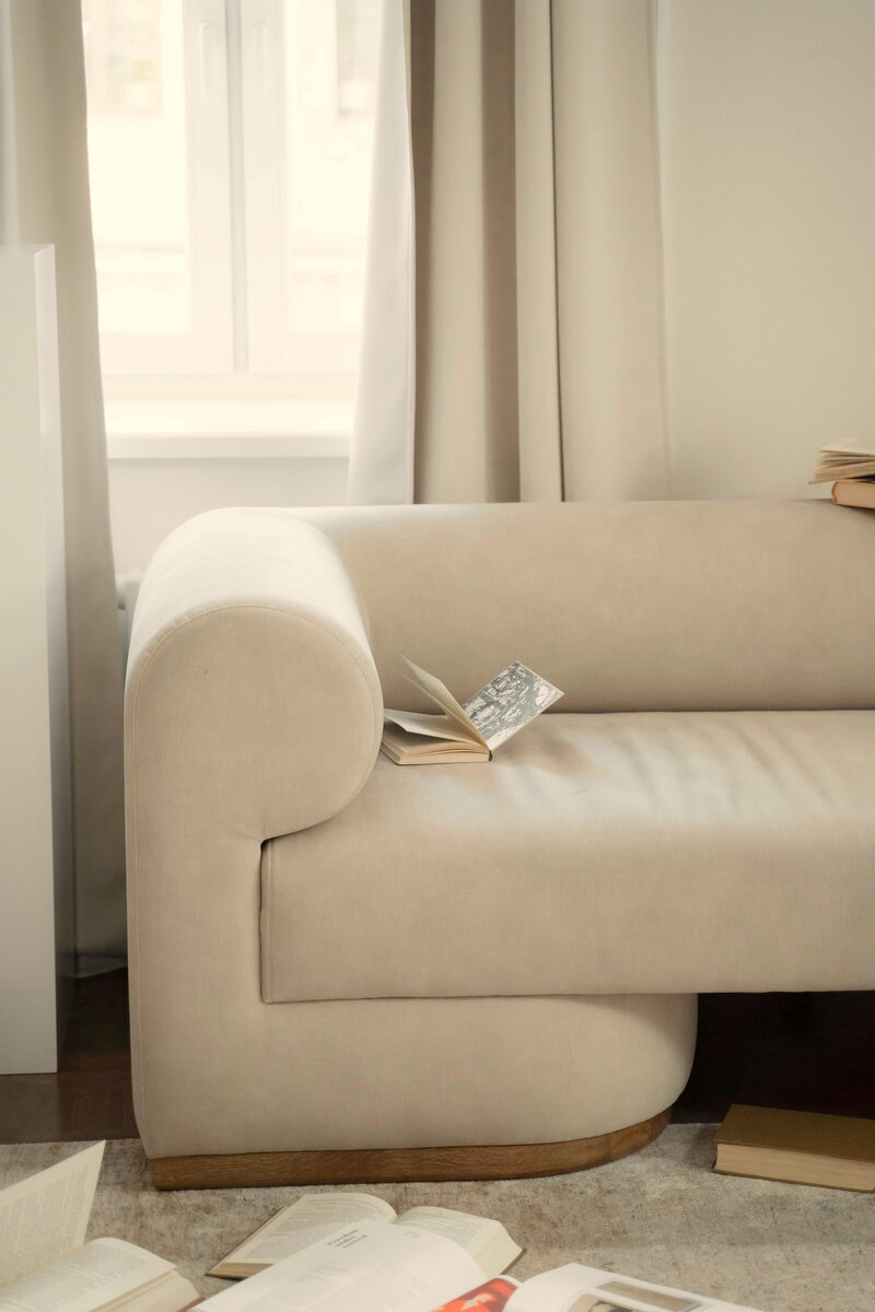 Modern white sofa with books laid atop in a light and airy room