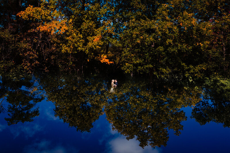 a wedding couple standing face to face as they are surrounded by trees and sky