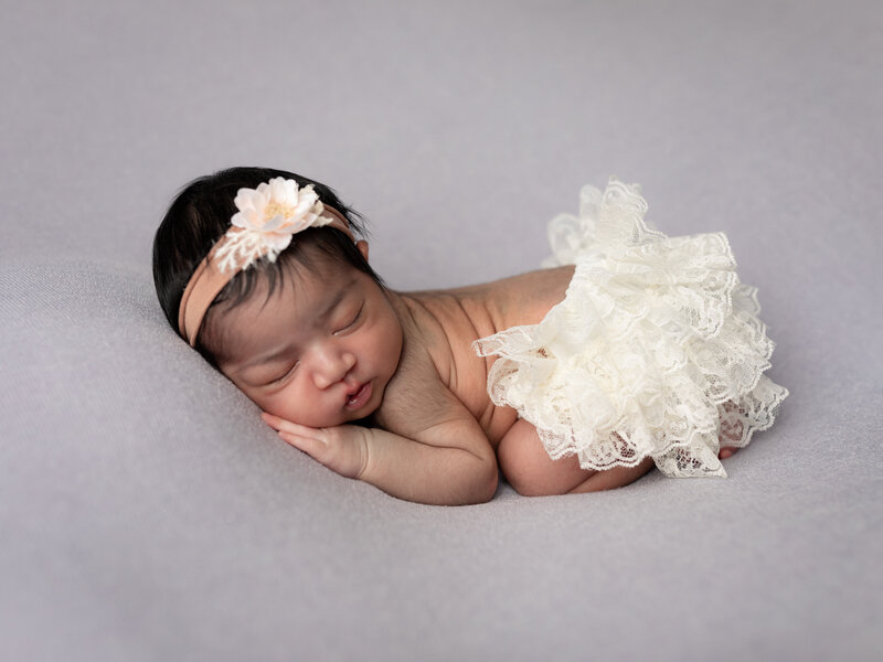 newborn baby girl in white tutu posed for newborn studio portraits