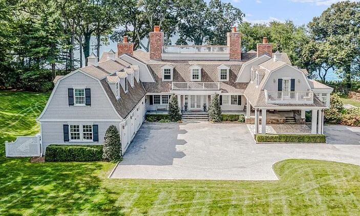 Aerial view of a renovated waterfront Colonial home in Centerport with Gambrel roof and multiple chimneys.