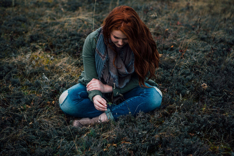 girl with red hair cross legged in grass