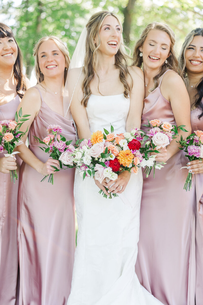 bride and bridesmaids holding flower bouquets while posing for a portrait