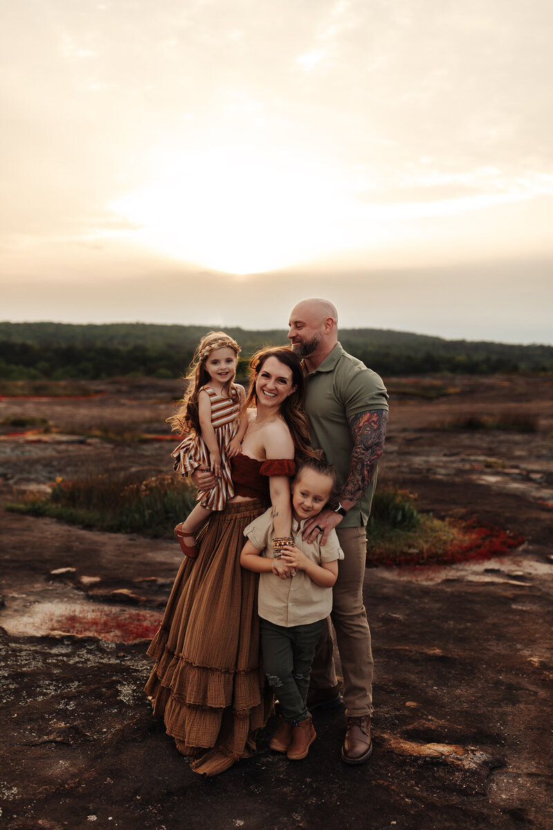 Family photography, family of four standing closely together with hands on each other