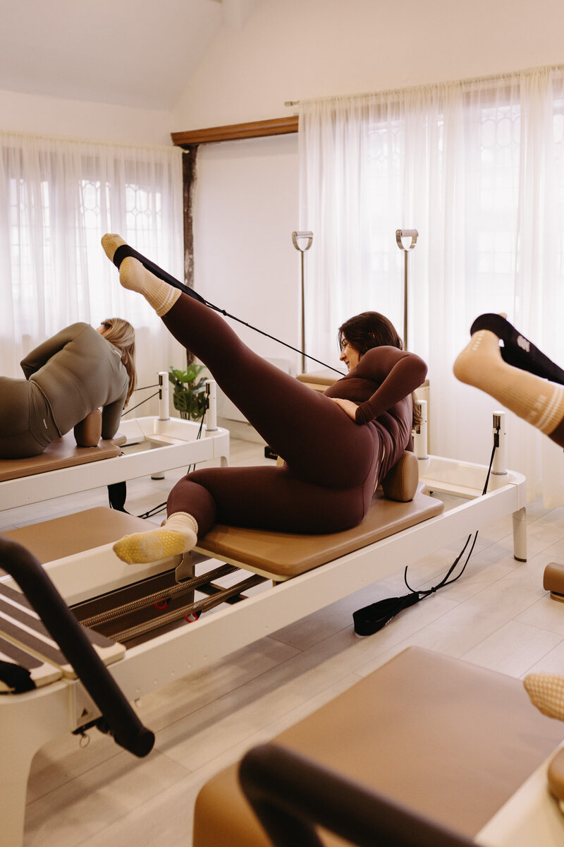 A man is in a pilates pose with his legs wide apart and arms stretched out.