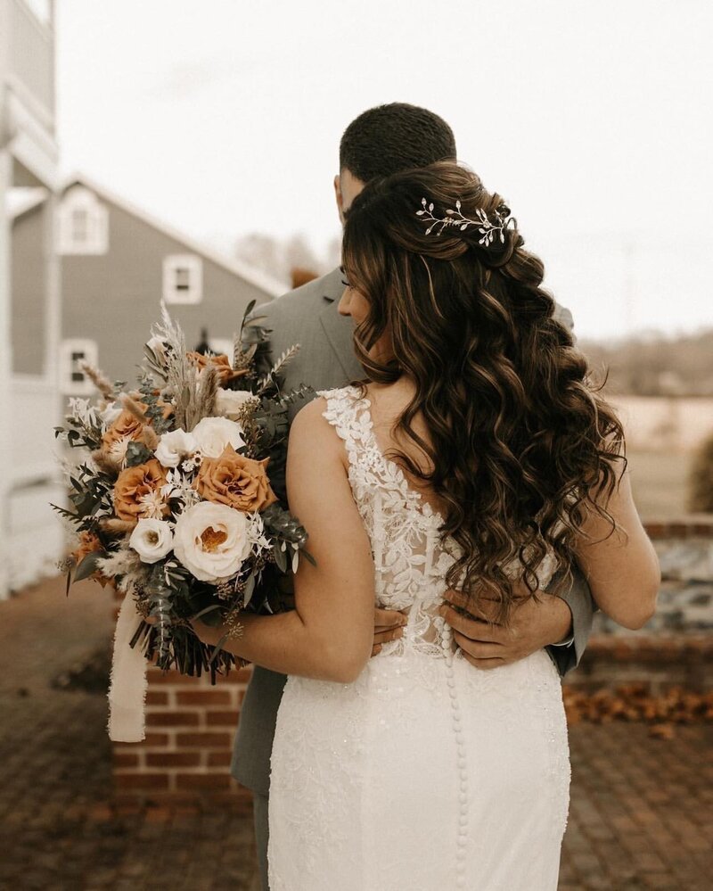 Bride with wavy braided wedding hair holding a bouquet of earth-toned flowers