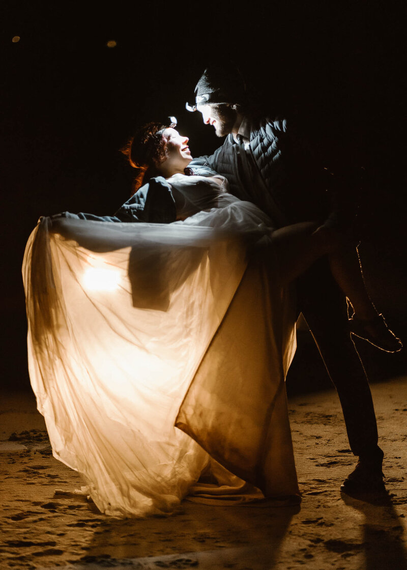 To end their Oregon Coast elopement, a couple dances by the light of their car.