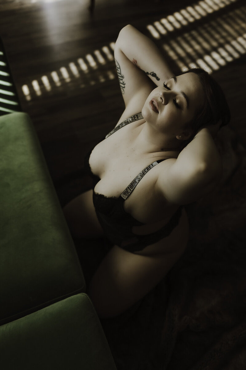 Striking contrast between soft skin and dark, moody lighting, enhancing the sensuality of the boudoir composition.