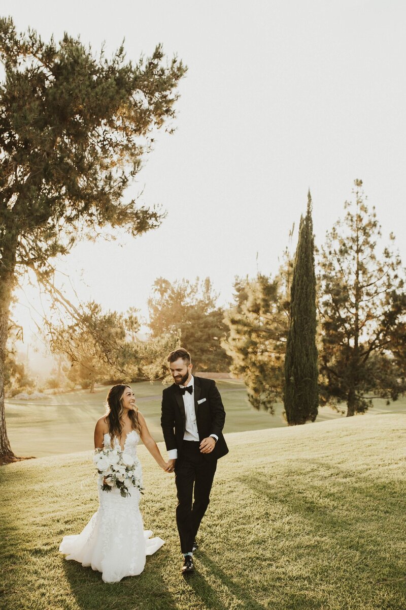 bride and groom look at each other as they walk while taking their wedding photos