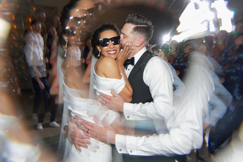 Groom kisses bride on the dance floor during their wedding reception.