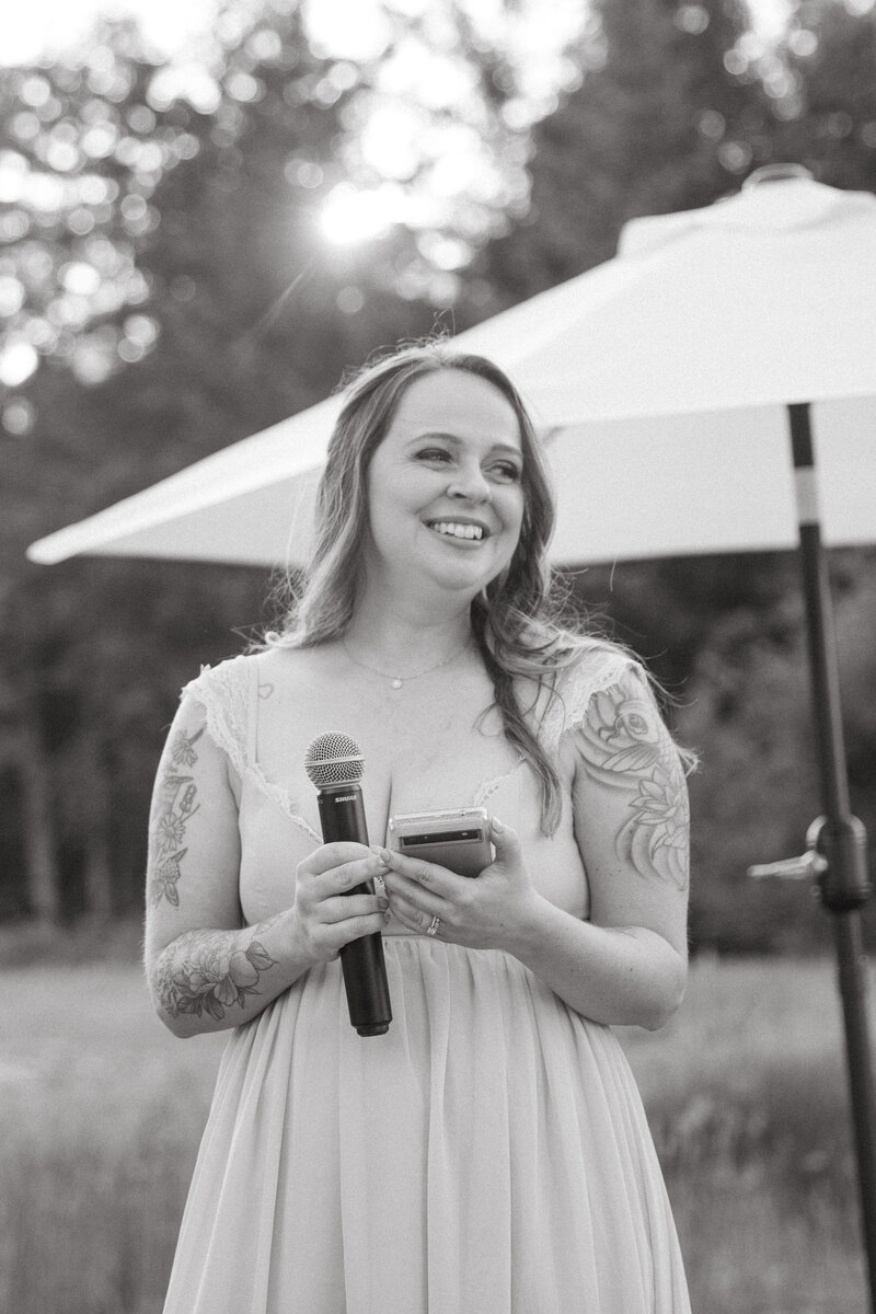 A guest is standing with a huge smile on her face before she gives a toast to the couple.