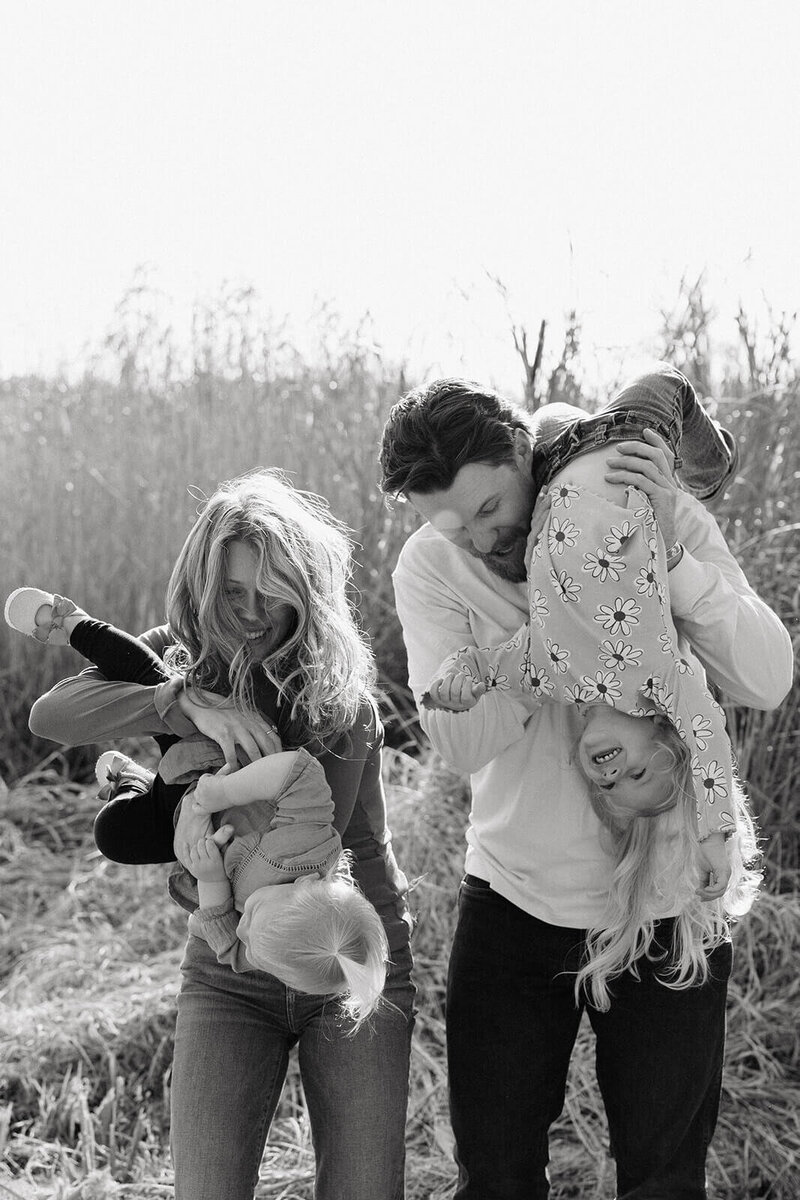 Playful parents hold their daughters upside down