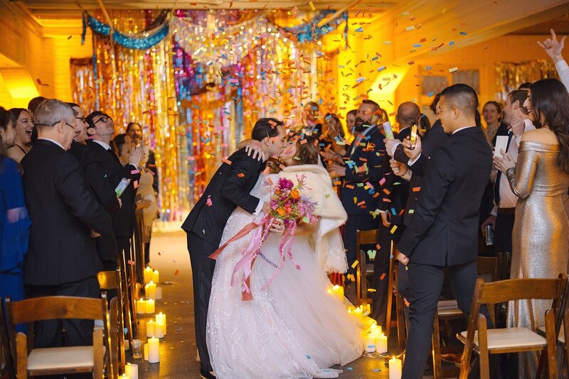 A couple kissing in the aisle with confetti.