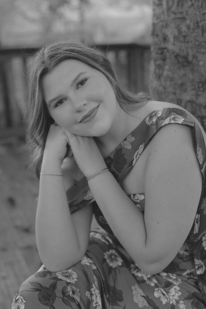A young woman sitting on a parking bench with her hands near the side of her face at Steele Creek Park in Bristol, TN. Northeast, TN Lifestyle Senior Photographer. 