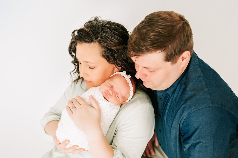 newborn photo of newborn baby sleeping on moms shoulder with dad cuddling nearby