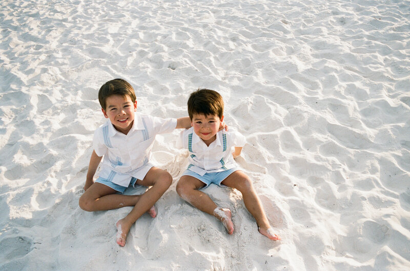 35mm film photographer brothers hugging on the beach 