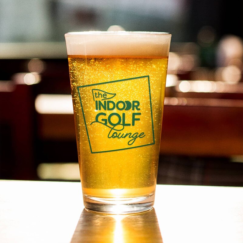 The Indoor Golf Lounge logo printed on a pint glass full of beer